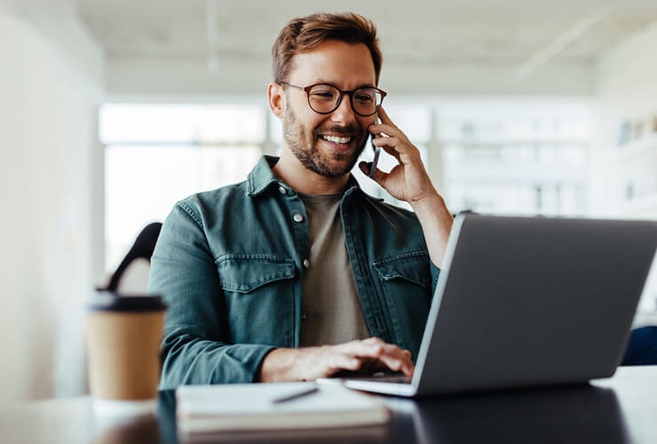 Man on mobile phone and laptop switching phone carriers